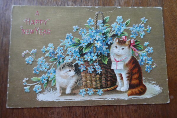 two cats standing by blue flower in a basket a new years antique postcard